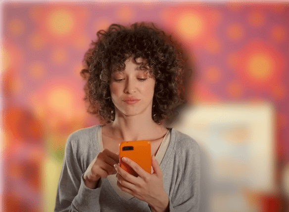 Temu commercial actress with Curly hair and orange dress
